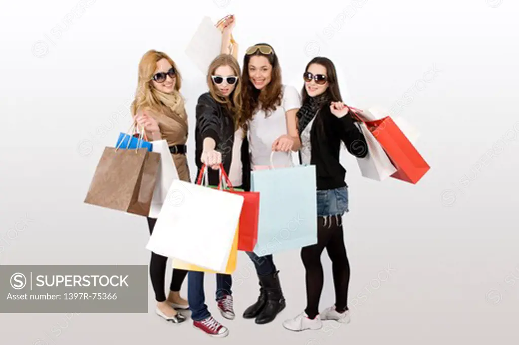 Four young women standing together with shopping bags, Shopping