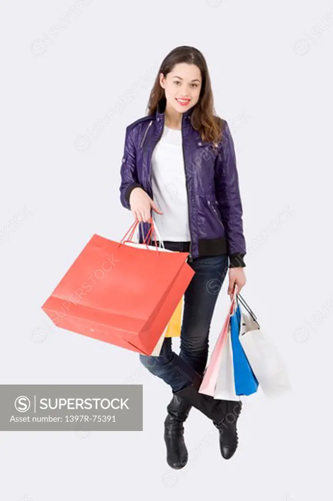 Young woman standing with shopping bags and smiling at the camera, Shopping