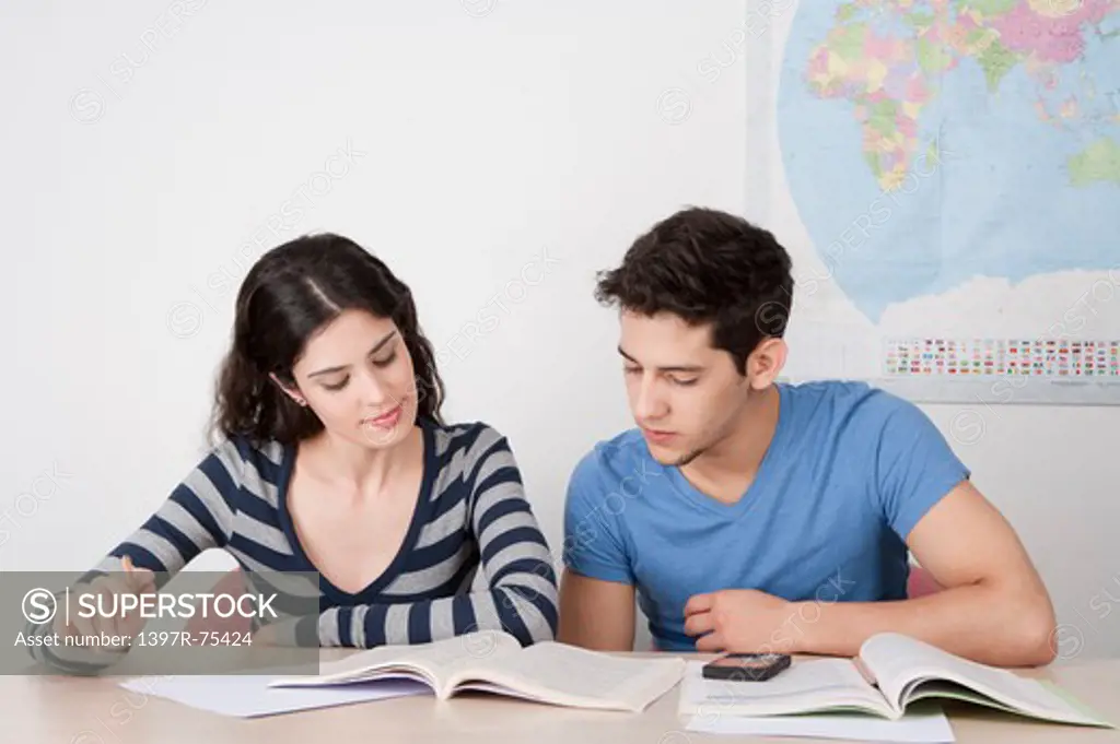 Two young friends sitting in classroom, studying