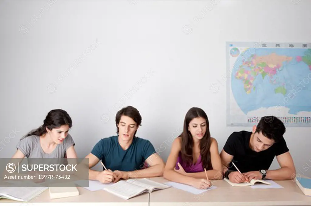 Four students sitting in classroom, writing