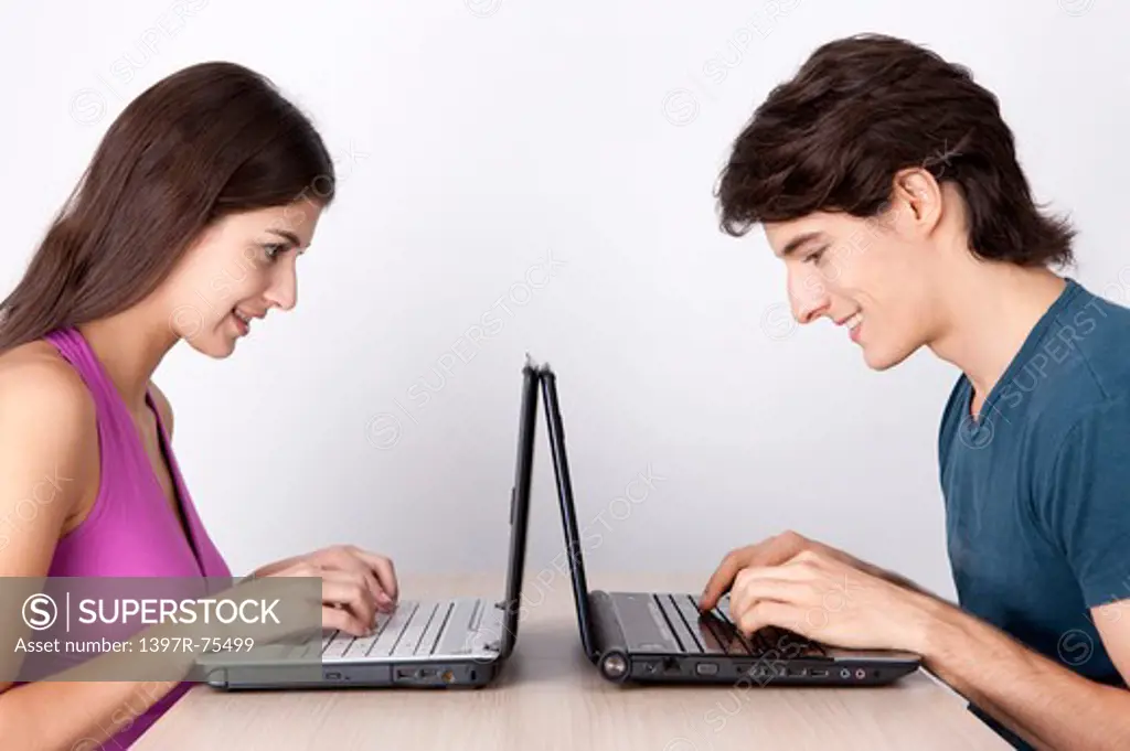 Two young friends using laptops