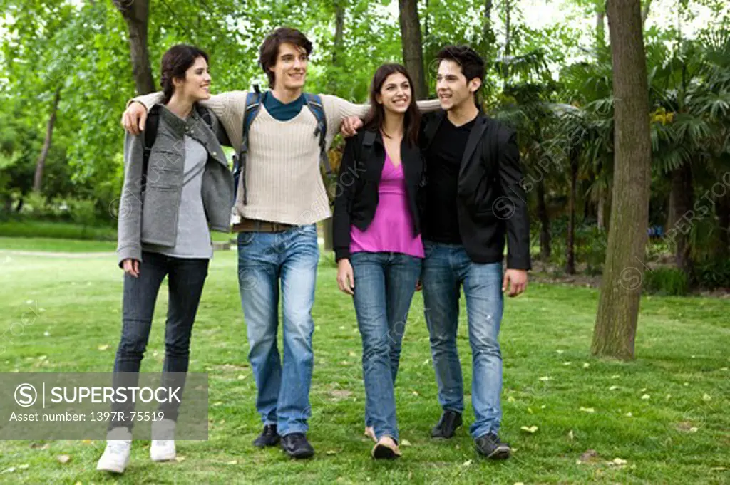 Four friends walking arm in arm in a park