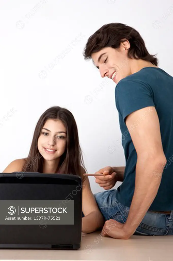 Young couple looking at a laptop, man sitting on the desk