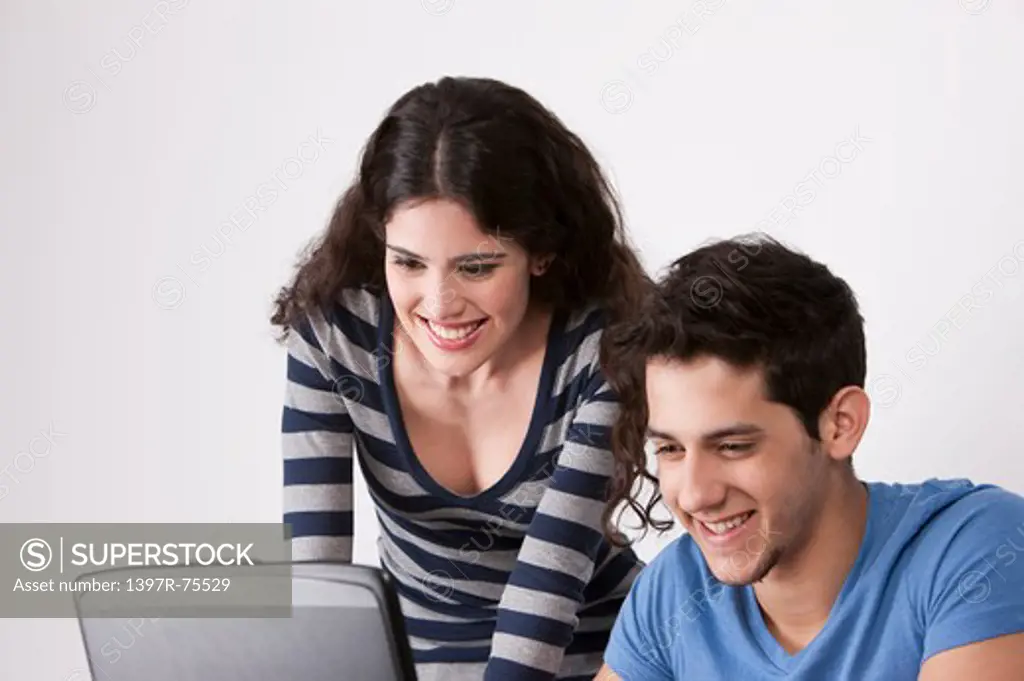 Two young friends looking at a laptop, smiling
