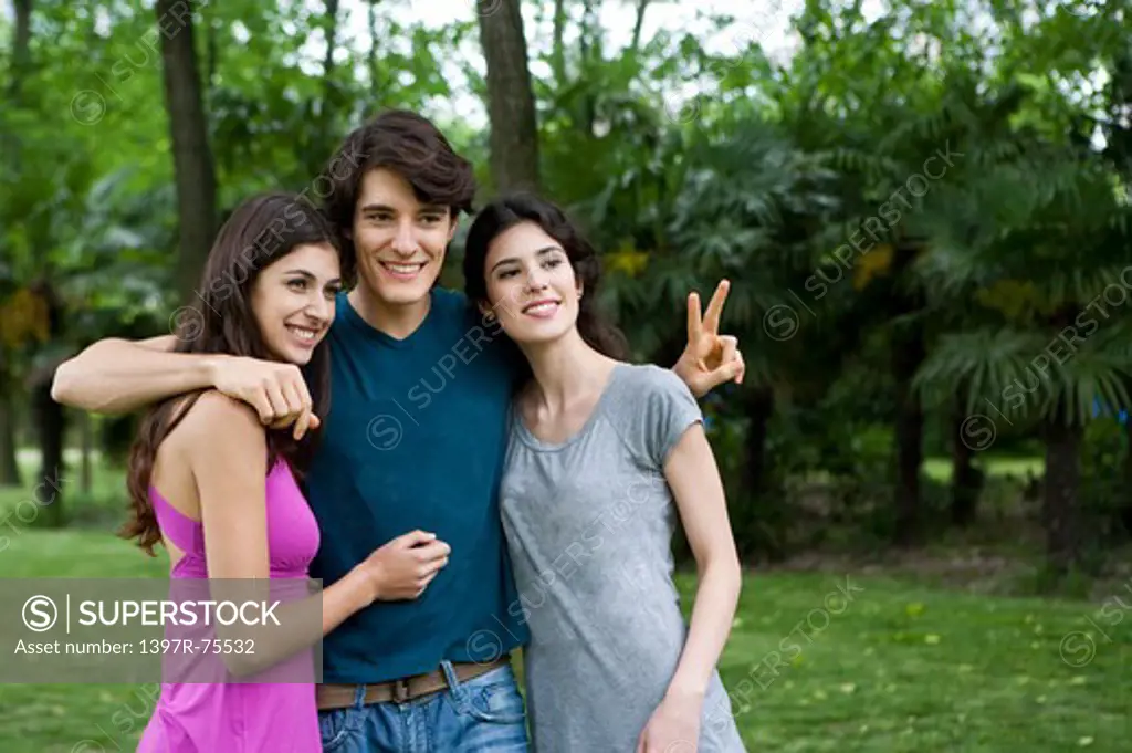 Three young friends standing arm in arm, smiling