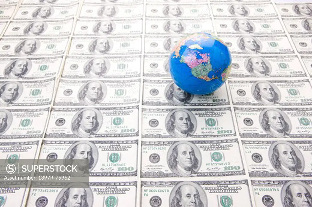 A toy globe on rows of hundred dollar bills