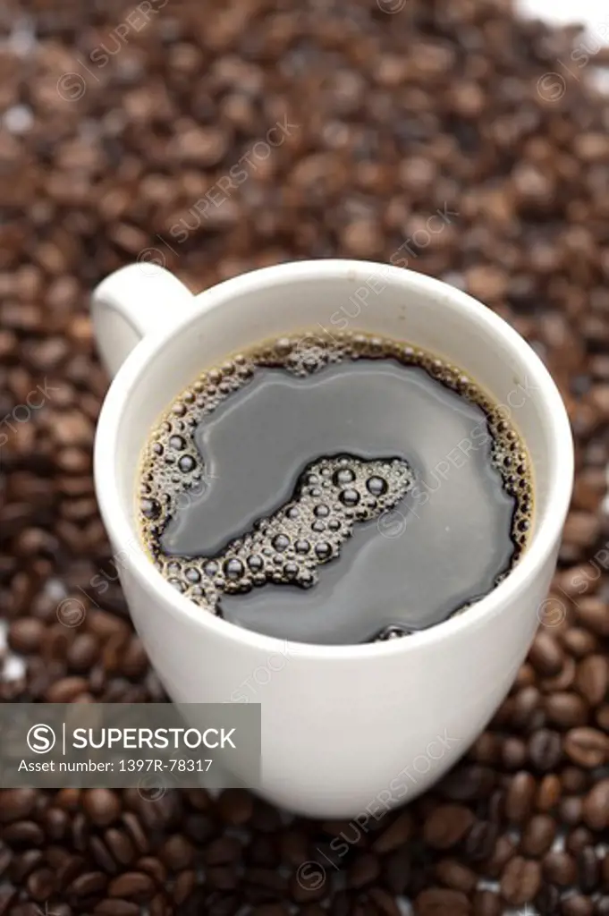 Close-up of a cup of coffee and coffee beans in background