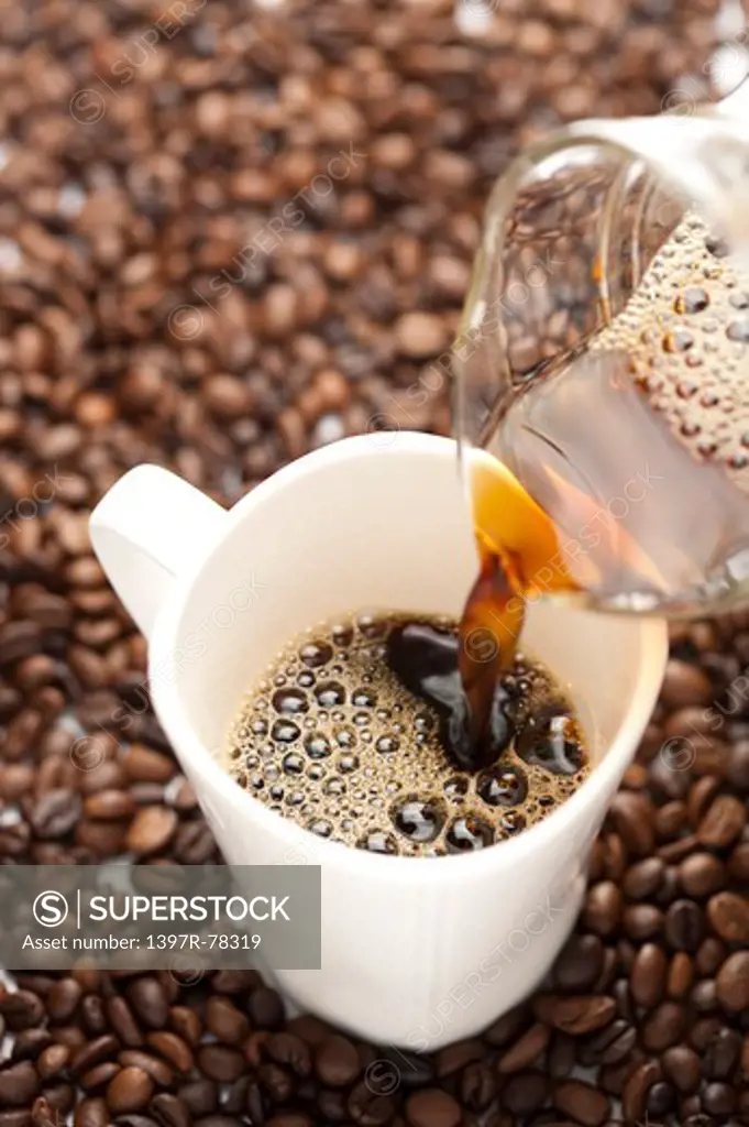 Close-up of pouring coffee and coffee beans in background