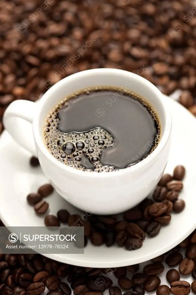 Close-up of a cup of coffee and coffee beans in background