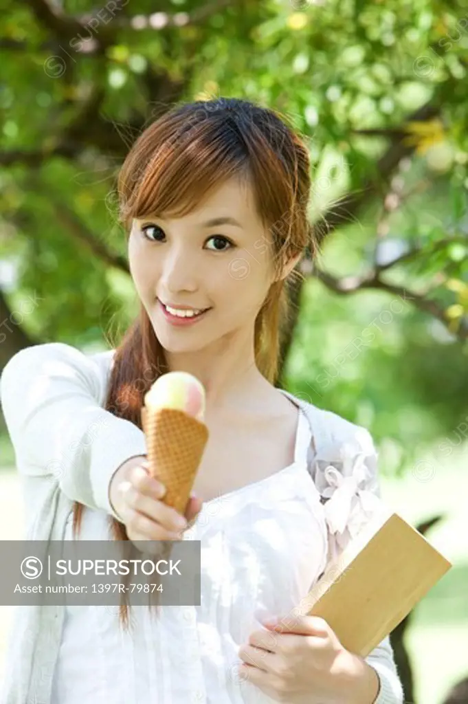 Young woman holding ice cream and book with smile