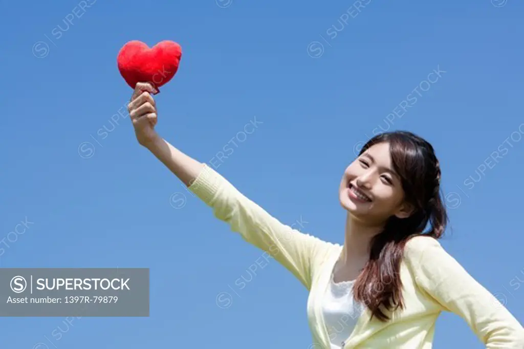 Young woman holding heart shape and smiling