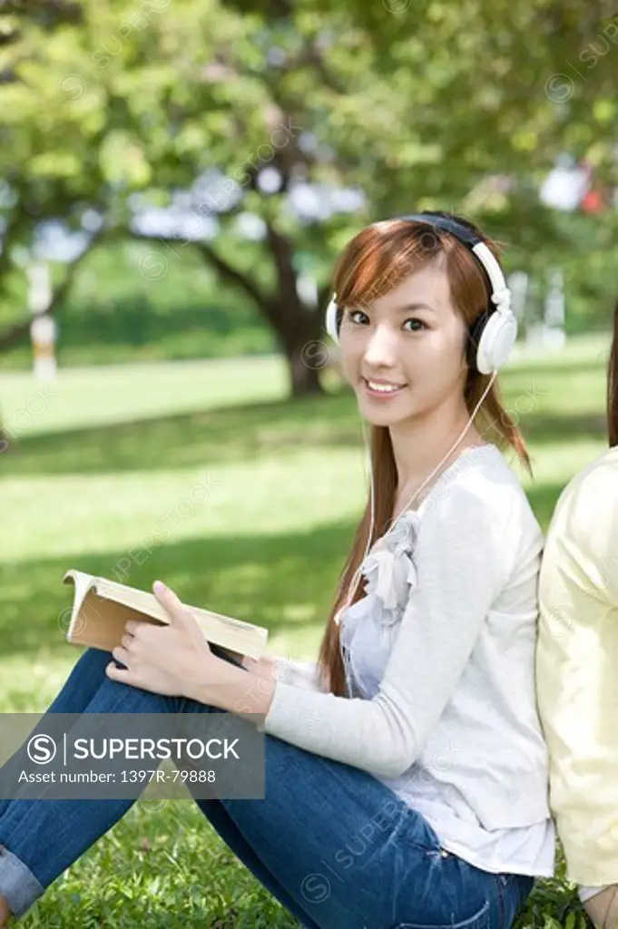 Young woman holding a book and wearing headphone with smile