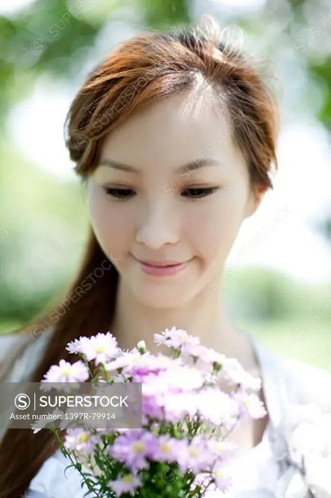 Young woman holding a bunch of flowers and looking down with smile