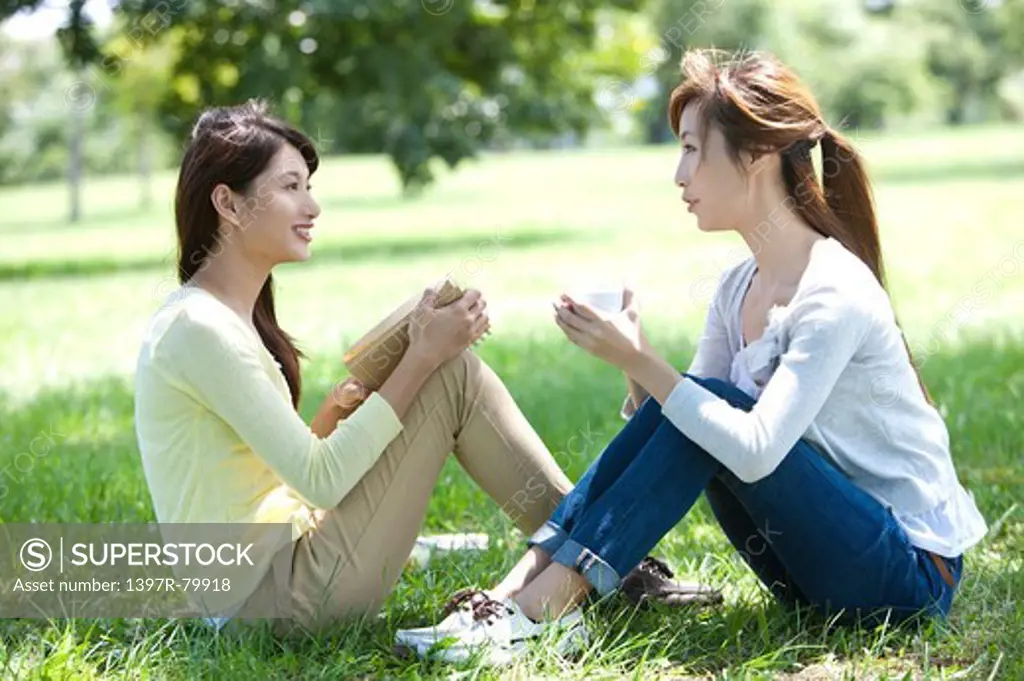 Young women sitting on the lawn and talking