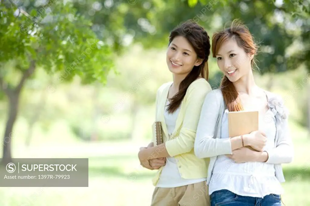 Young women holding book and looking away with smile
