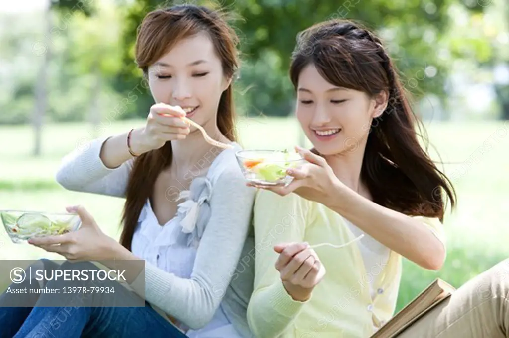 Young women holding spoon and sitting with smile