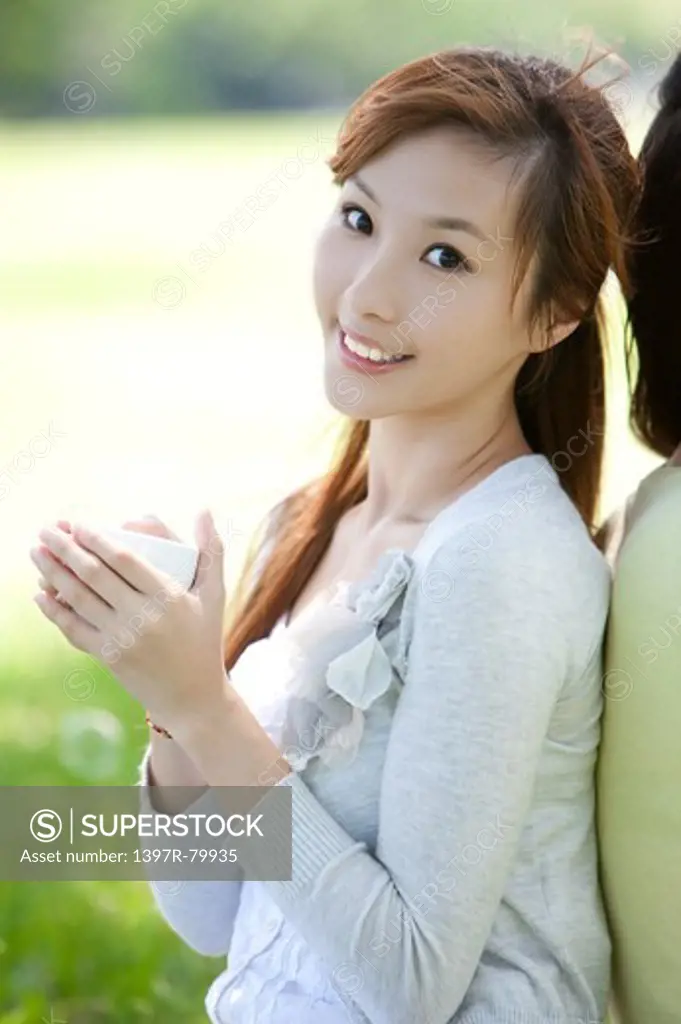 Young woman holding a cup and smiling at the camera
