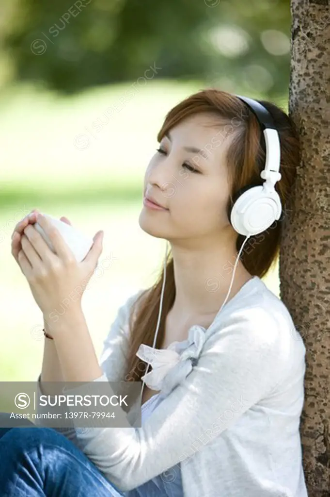 Young woman listening music and holding a cup