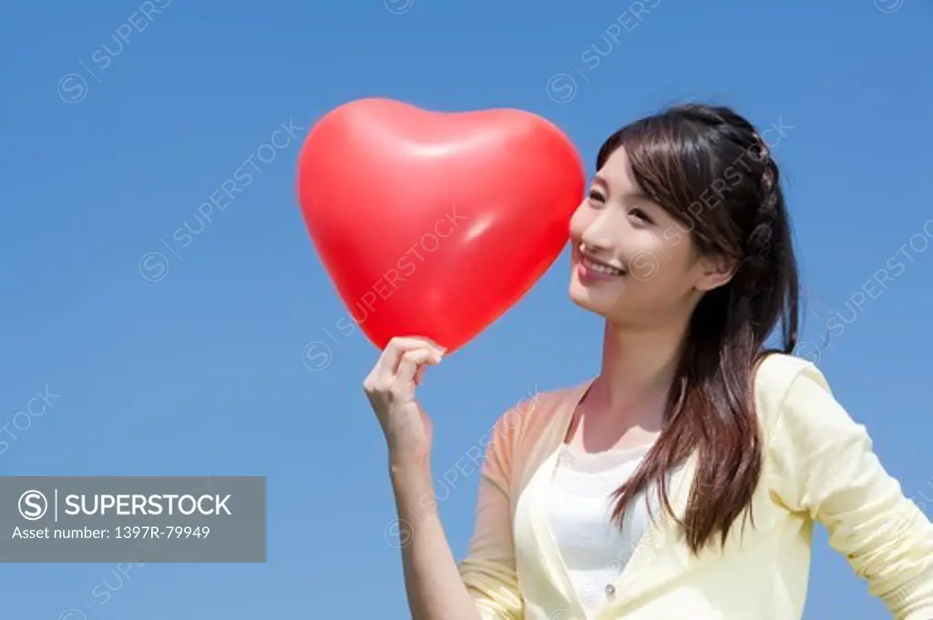 Young woman holding balloon and looking away with smile