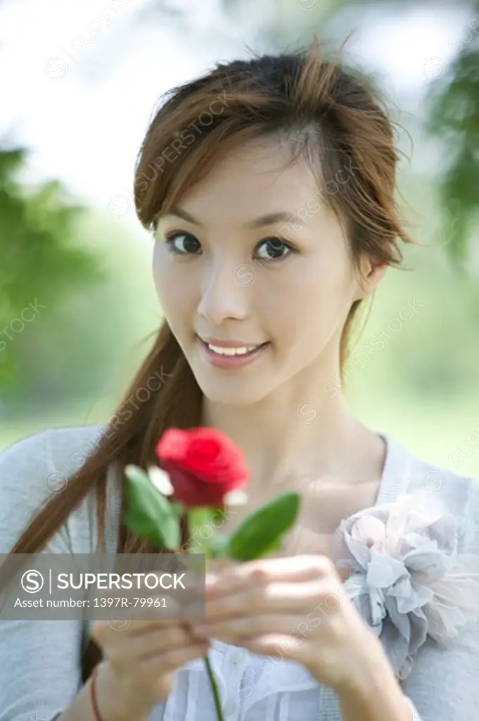 Young woman holding a flower and smiling at the camera
