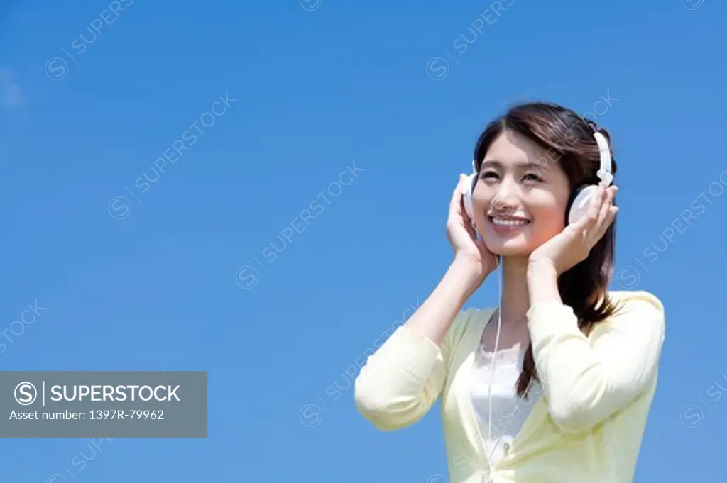 Young woman wearing headphone and looking away with smile