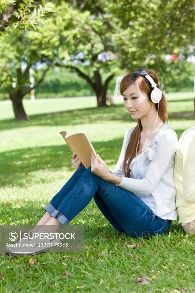 Young women sitting on the lawn and reading book
