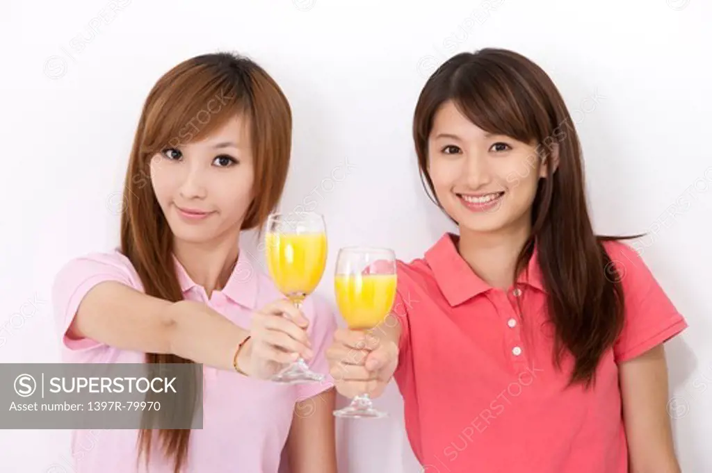 Young women holding glass of juice and smiling at the camera