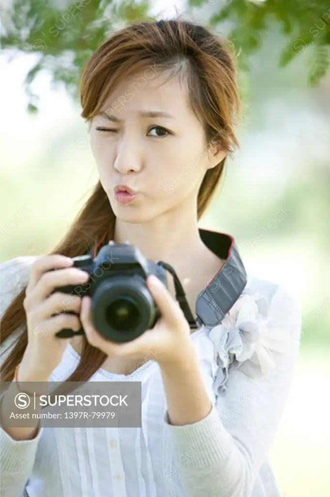 Young woman holding camera and looking at the camera