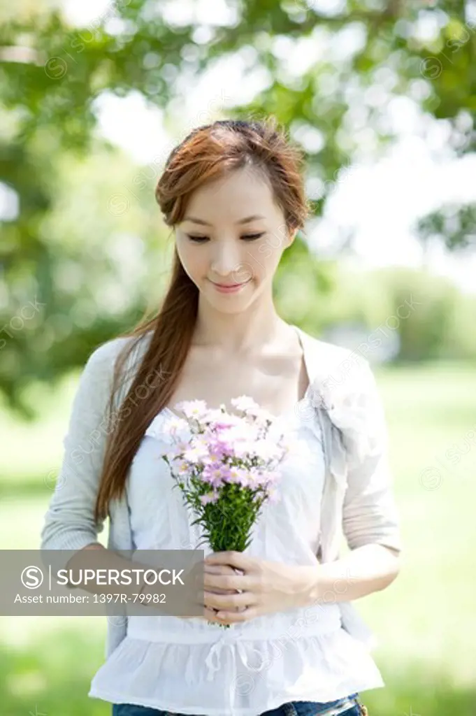 Young woman holding a bunch of flowers and looking down with smile