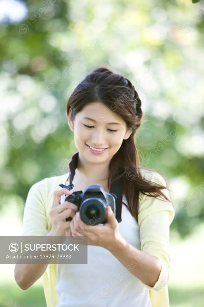 Young woman photographing and looking down with smile