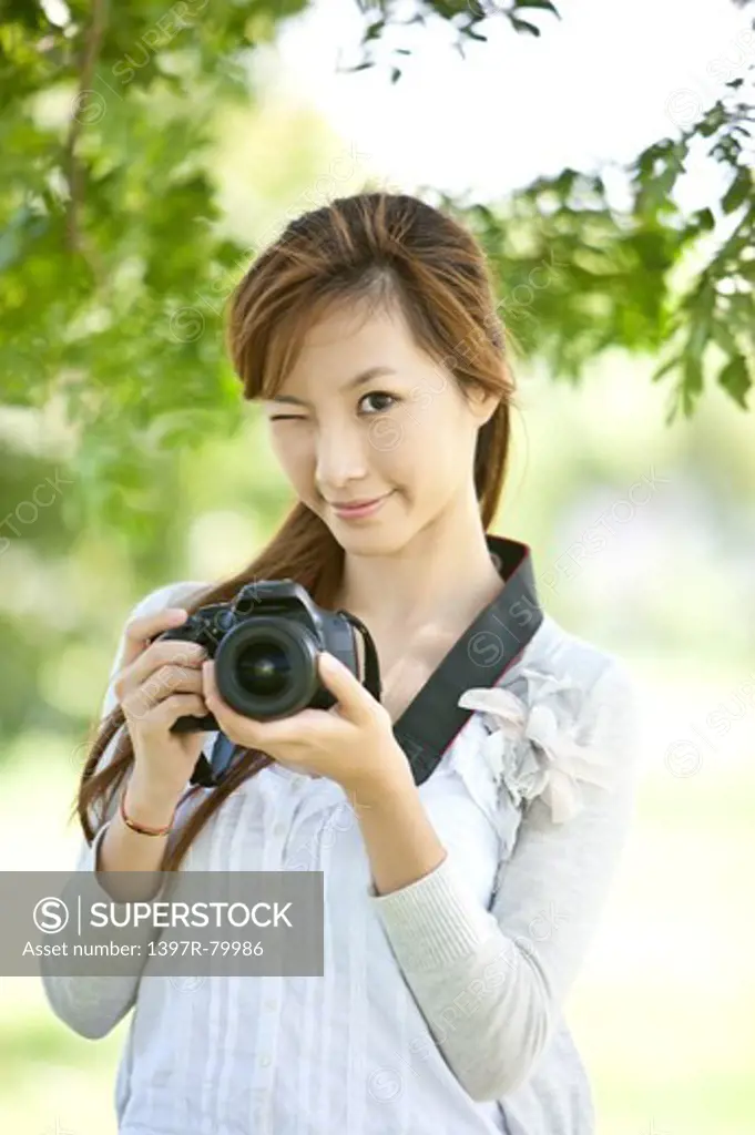 Young woman holding camera and smiling at the camera