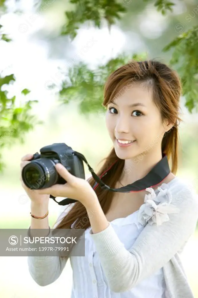 Young woman holding camera and smiling