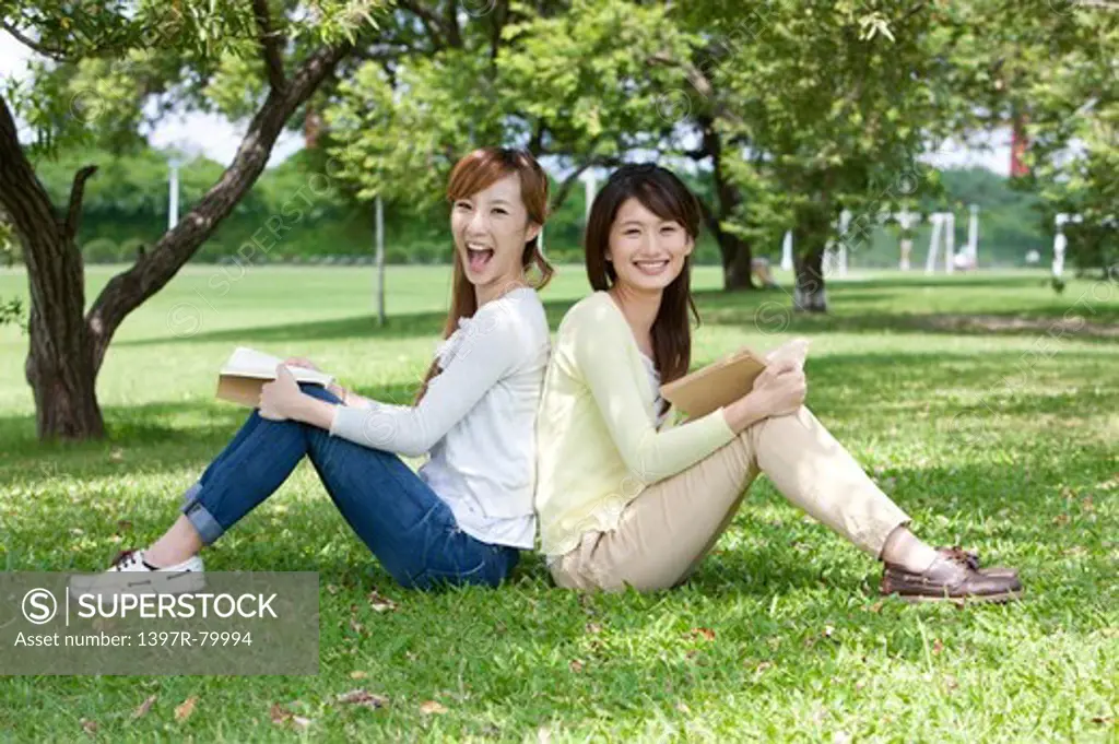 Young women sitting on the lawn and smiling happily