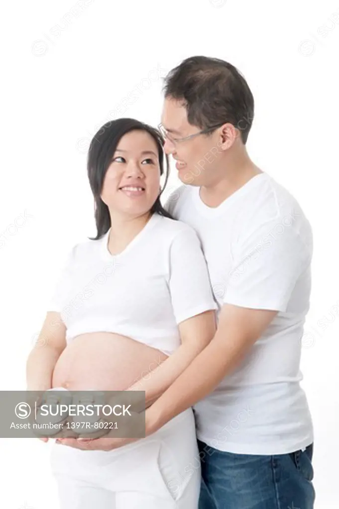 Pregnant woman holding baby booties and smiling with man