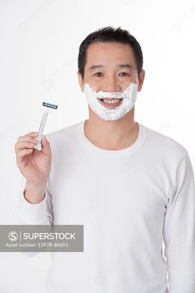 Mature man holding razor and smiling at the camera