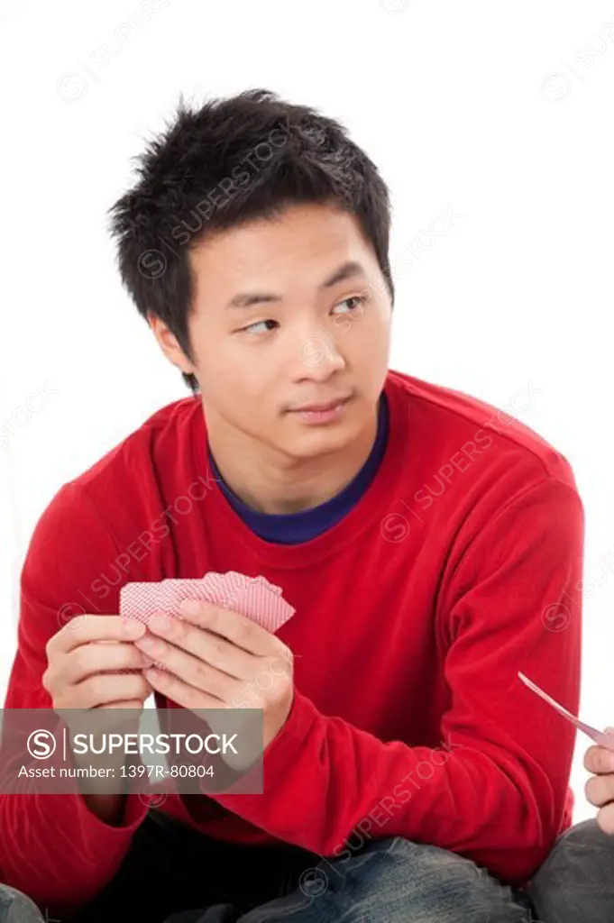 Teenage boy looking away and playing poker