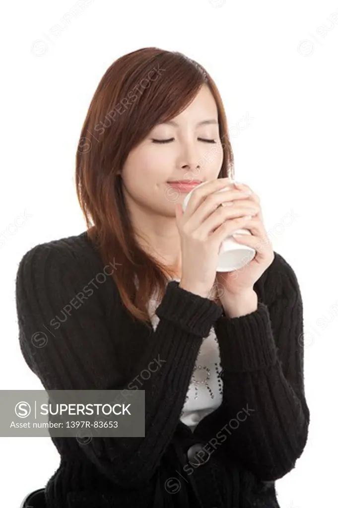 Beautiful young woman holding a cup, eyes closed