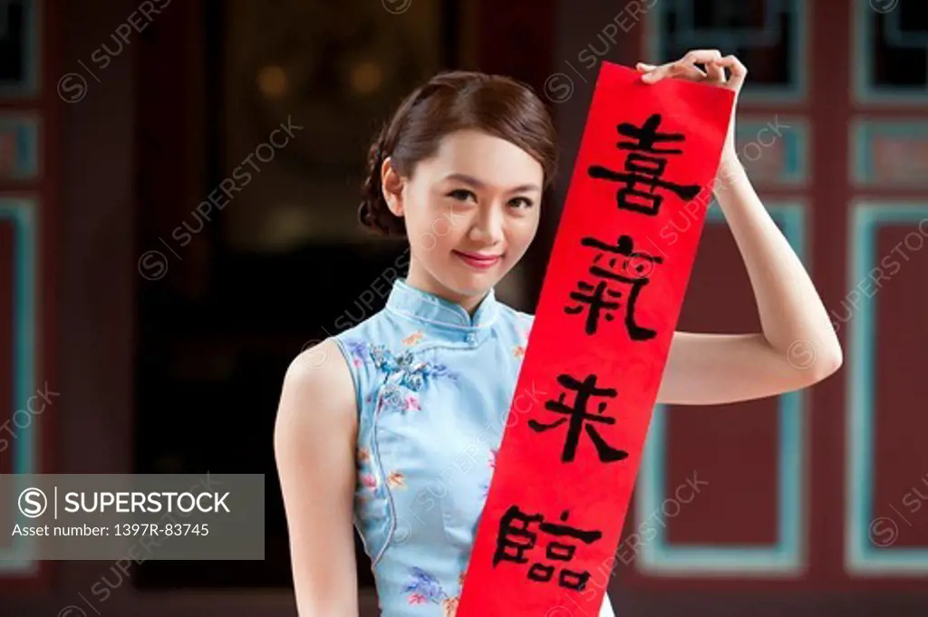 Young woman wearing cheongsam and holding couplet with smile
