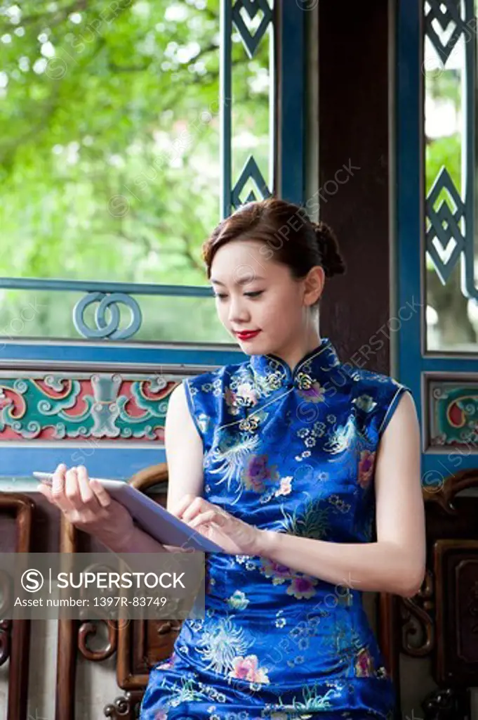 Young woman wearing cheongsam and looking down with smile