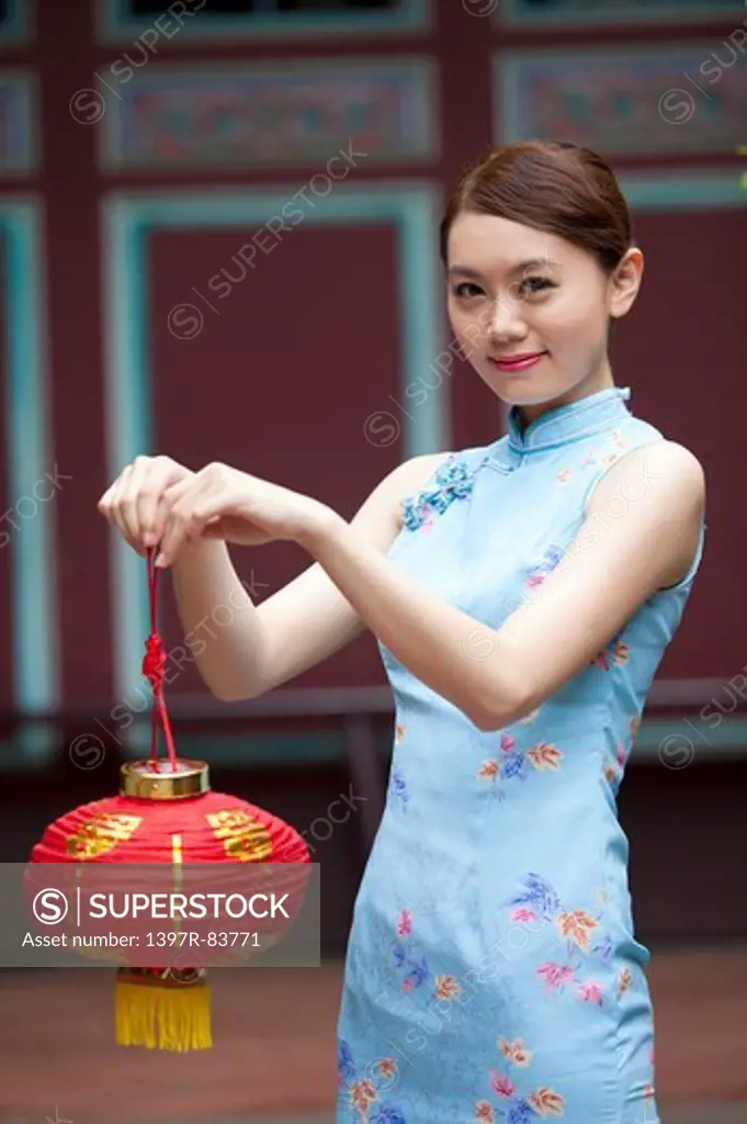 Young woman with cheongsam holding paper lantern and smiling