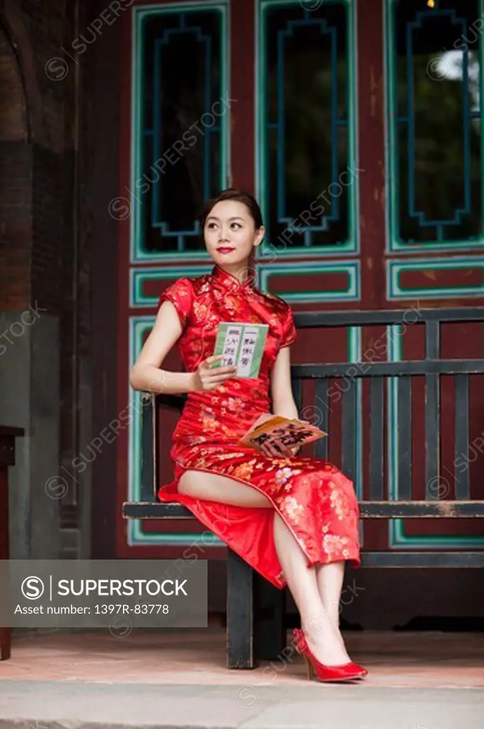 Young woman with cheongsam sitting and looking away with smile