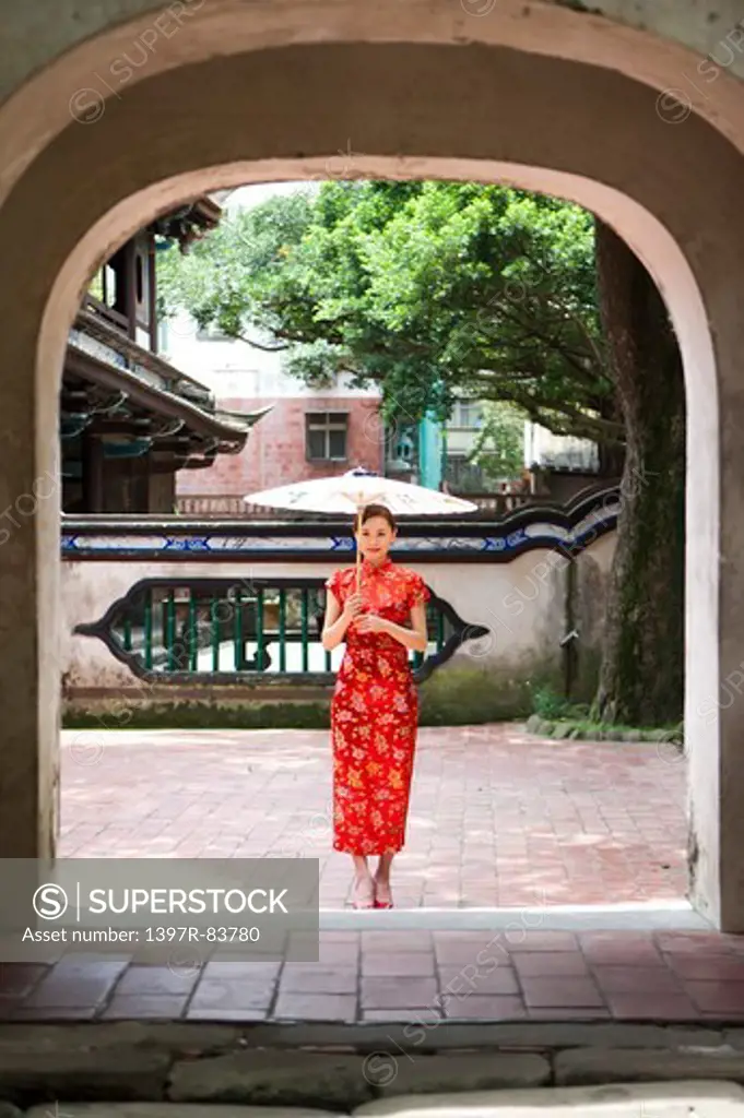 Young woman with cheongsam standing and holding paper umbrella
