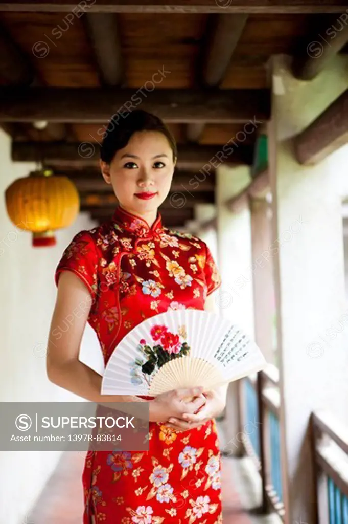 Young woman with cheongsam holding folding fan with smile