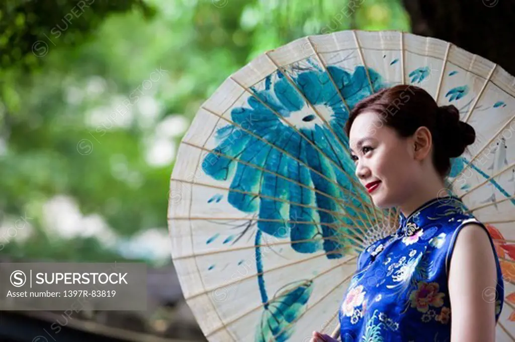 Young woman with cheongsam holding paper umbrella with smile