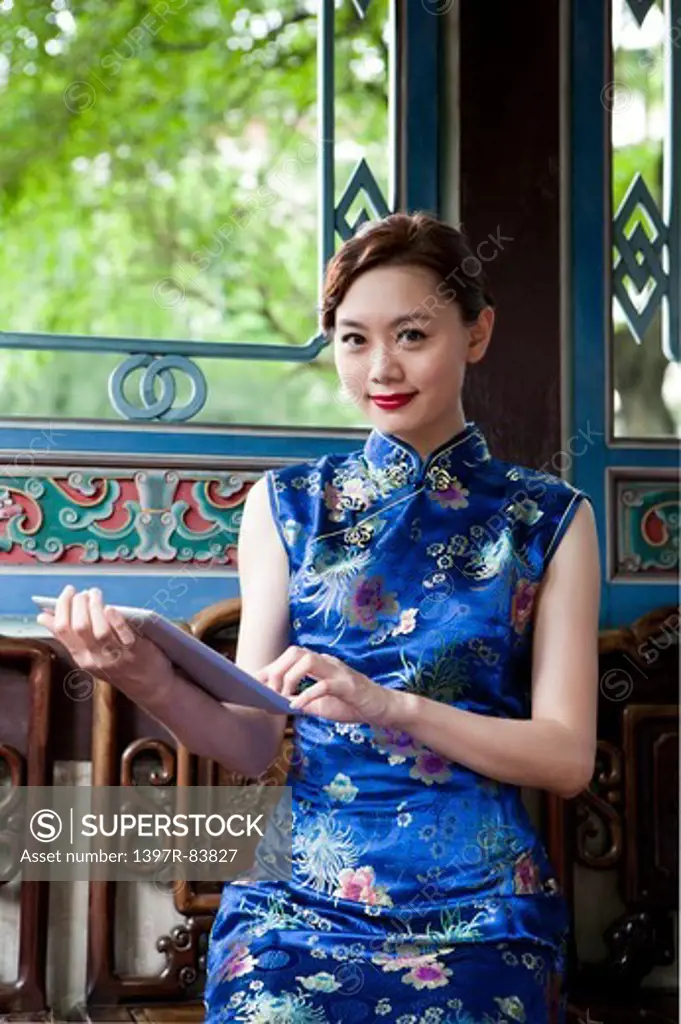 Young woman with cheongsam holding pad and looking at the camera
