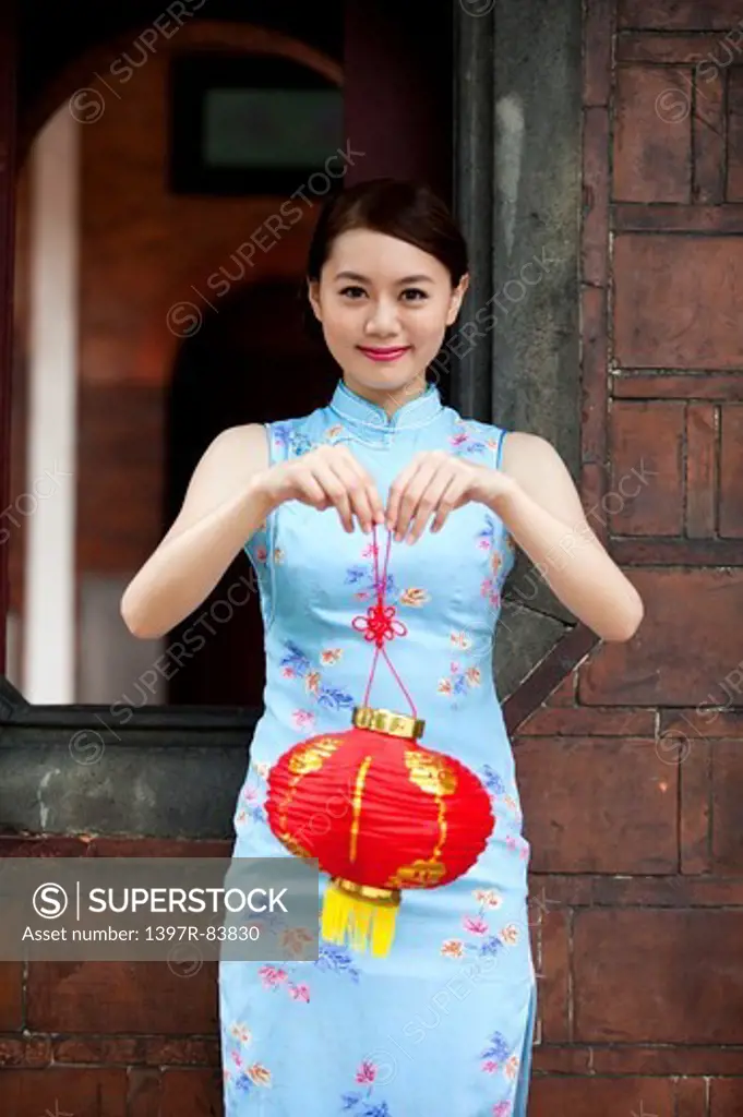 Young woman with cheongsam holding paper lantern with smile