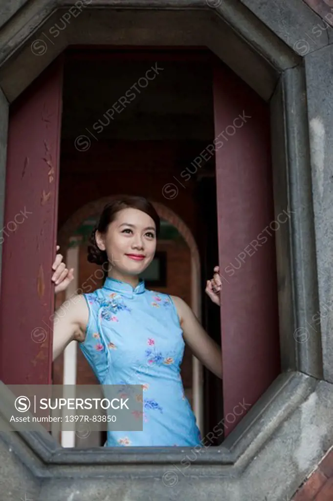 Young woman wearing cheongsam and looking away with smile