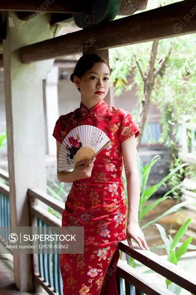 Young woman wearing cheongsam and holding folding fan