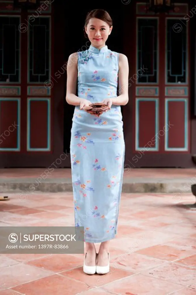 Young woman wearing cheongsam and holding food with smile