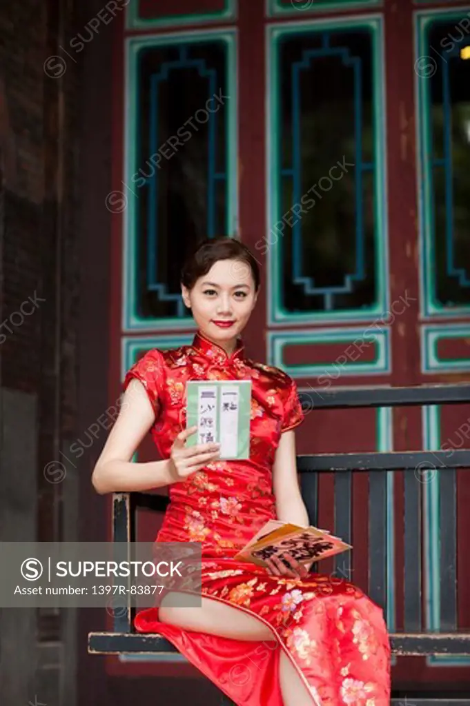 Young woman wearing cheongsam and sitting with smile